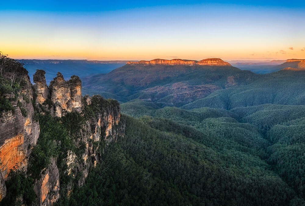 A scenic view of blue mountains at sunset.